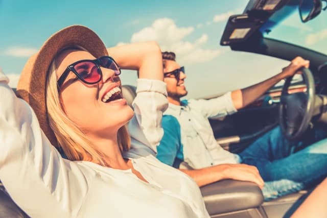 Two friends enjoying a sunny drive in a convertible with Drive mate